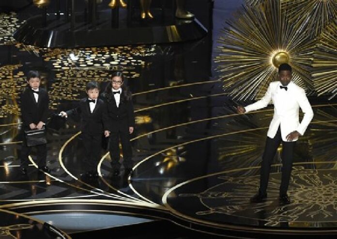 In this Sunday, Feb. 28, 2016 file photo, host Chris Rock, right, gestures to three unidentified children portraying auditors in a skit at the Oscars at the Dolby Theatre in Los Angeles. Photo: Pizzello/Invision / Associated Press