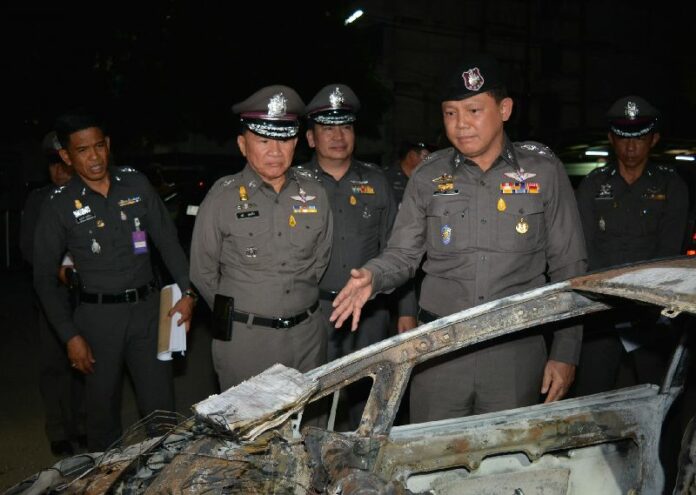 National police deputy commander Pongsapat Pongcharoen, at right, on Thursday night inspects the burned out remains of Ford Fiesta in the Sunday collision.
