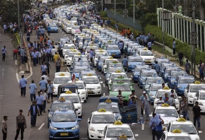 Taxis are lined up during a protest against competition from ride-hailing apps such as Uber and Grab at the main business district in Jakarta, Indonesia, Tuesday, March 22, 2016. Photo: Achmad Ibrahim / Associated Press