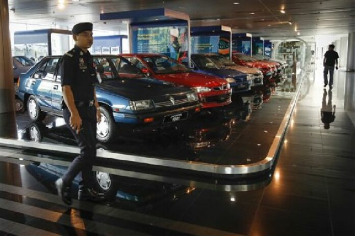 A Malaysian policeman walks by a fleet of national cars on display at the Proton Centre of Excellence Complex in Kuala Lumpur, Malaysia, Tuesday, March 1, 2016. Photo: Joshua Paul / Associated Press