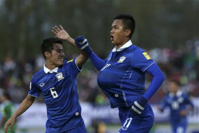 Mongkol Thosakrai, at right, holds the ball under his shirt as he celebrates a goal against Iraq with teammate Sarach Yooyen during a qualifying match Thursday in Tehran, Iran. Photo: Vahid Salemi / Associated Press