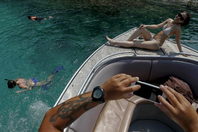 A tourist poses for a photograph on a boat near Maiton island in Phuket, Thailand March 18, 2016. Photo: Athit Perawongmetha / Reuters