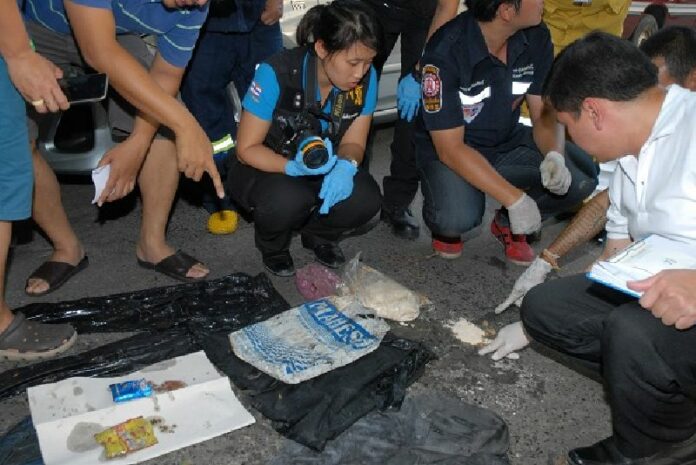 Police and rescue workers inspect items found inside a bag containing a corpse discovered in a Bangkok canal Sunday afternoon.