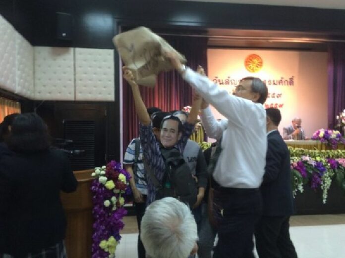 Wearing masks of Prime Minister Prayuth Chan-ocha and waving a banner opposing the draft constitution, activists from the League of Liberal Thammasat for Democracy are intercepted by university staff on Tuesday north of Bangkok. Photo: Anuthee Dejthevaporn