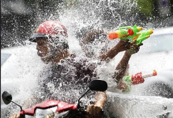 In this April 13, 2015 file photo, people riding on a motorbike react as a boy splashes water on them during the traditional Thai New Year celebrations or Songkran water festival in Bangkok. Photo: Sakchai Lalit / Associated Press