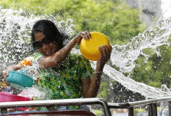 In this April 13, 2015 file photo, a woman splashes water on people from the back of a truck during the Songkran water festival in Bangkok. Photo: Sakchai Lalit / Associated Press