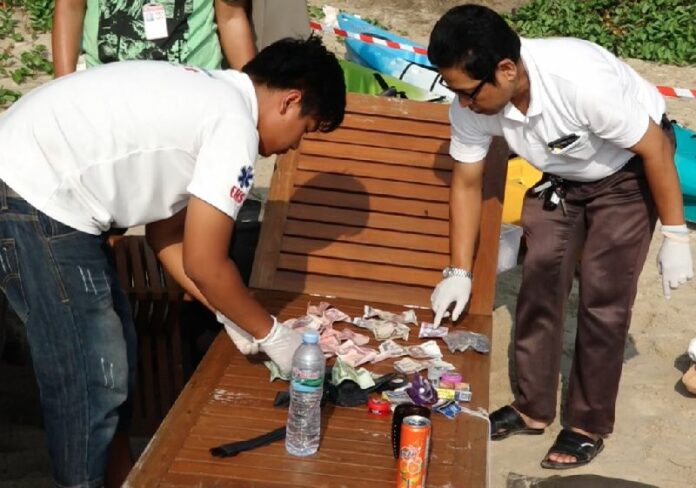 Emergency responders search through the belongings of a tourist who died Saturday on Koh Samui