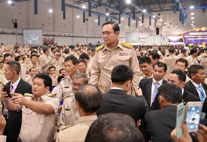 Junta chairman and Prime Minister Gen. Prayuth Chan-ocha stands tall for a selfie with uniformed bureaucrats Monday in Bangkok.