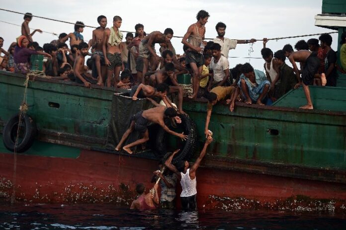 Rohingya migrants passing food supplies dropped by a Royal Thai Navy helicopter to others in May, 2015, near Koh Lipe. Photo: Christophe Archambault / Facebook<br />