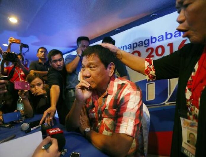 Front-running presidential candidate Mayor Rodrigo Duterte is prayed over by a supporter during a news conference shortly after voting in a polling precinct at Daniel R. Aguinaldo National High School, Matina district, his hometown in Davao city in southern Philippines Monday, May 9, 2016. Photo: Bullit Marquez / Associated Press