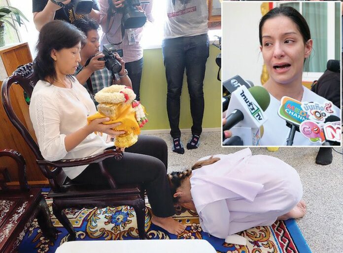 B-movie actress Anna Reese on her knees before Chanthana Wongbundit, the wife of the policeman she killed by driving her Mercedes-Benz into his car, where he was sleeping on the side of the road.