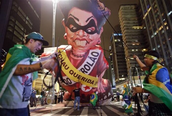 Anti-government demonstrators set up a large inflatable doll in the likeness of Brazil's President Dilma Rousseff wearing a presidential sash with the words in Portuguese "Goodbye dear" and "Mother of big oil" written on it, in Sao Paulo, Brazil, Wednesday, May 11, 2016. Photo: Andre Penner / Associated Press