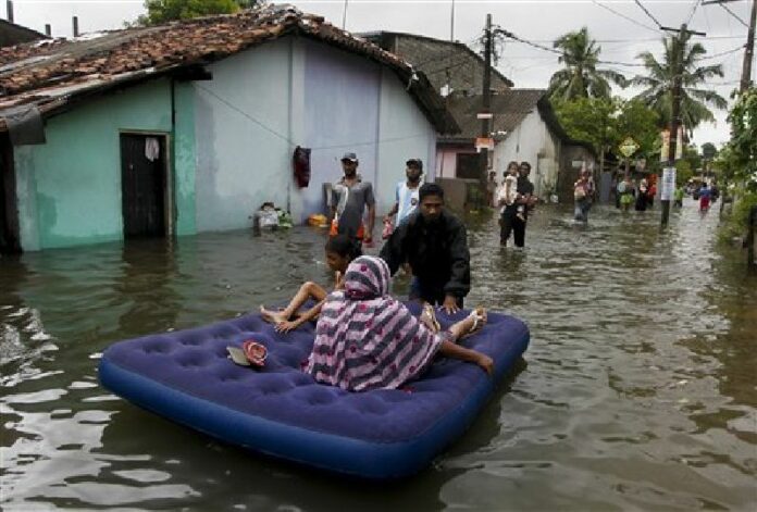 An elderly Sri Lankan woman and a girl are shifted on a mattress at a flooded area in Colombo, Sri Lanka, Tuesday, May 17, 2016. Photo: Eranga Jayawardena / Associated Press