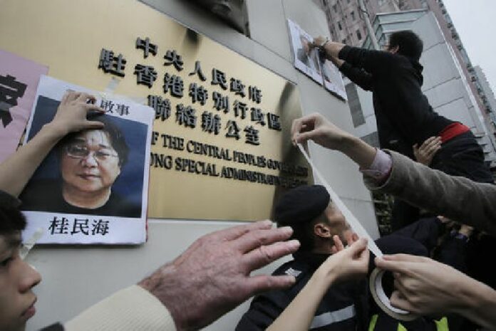 In this Jan. 3, 2016, file photo, protesters try to stick photos of missing booksellers, one of which shows Gui Minhai at left, during a protest outside the Liaison of the Central People's Government in Hong Kong. Photo: Vincent Yu / Associated Press