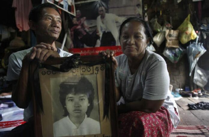 In this Aug. 1, 2013 file photo, Win Kyu, left, and his wife Khin Htay Win hold a portrait of their 16-year-old daughter Win Maw Oo, who was killed during pro-democracy protests brutally crushed by Myanmar's military 28 years ago, in their house in Yangon, Myanmar. Photo: Khin Maung Win / Associated Press