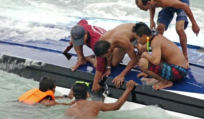 Rescue workers smash a hole in a capsized boat Thursday to pull a woman free off Koh Samui. Photo: Associated Press