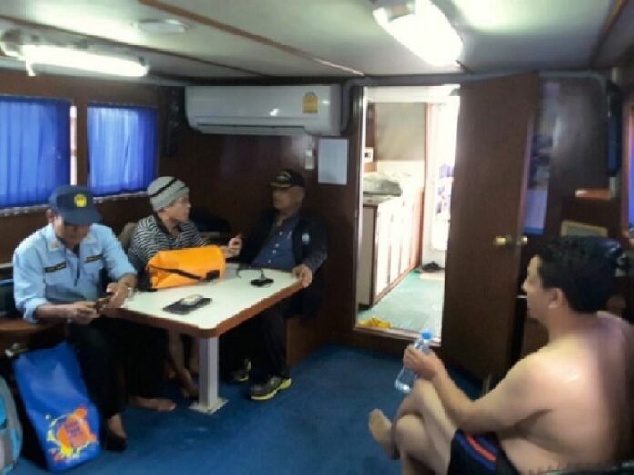 Zhou Hongzhi, at right, is questioned by marine protection officers Wednesday after he was caught feeding corn to coastal fish on an island beach in the southern province of Phang Nga.