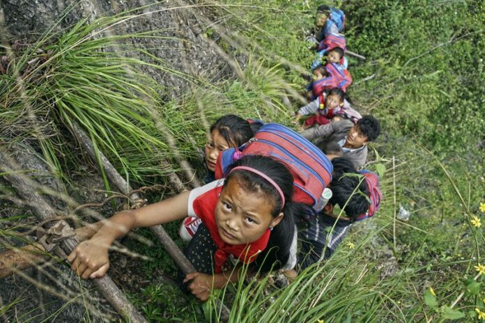 Children wearing their backpacks climb a cliff using a bamboo ladder on their way home from school in Zhaojue county, southwest China's Sichuan province. Photo: Chinatopix / Associated Press